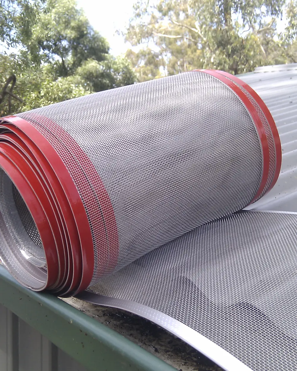 A roll of Leaf Free gutter mesh with its adhesive tape edge resting on a prepared roof