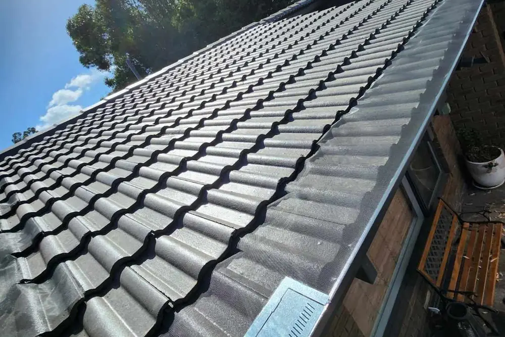 Leaf Free gutter mesh fitted along the gutter of a charcoal tiled roof against open sky